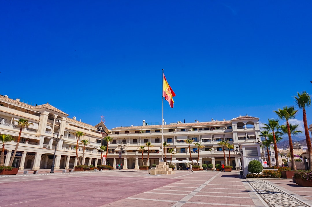 A spanish flag flies over a plaza and buildings.