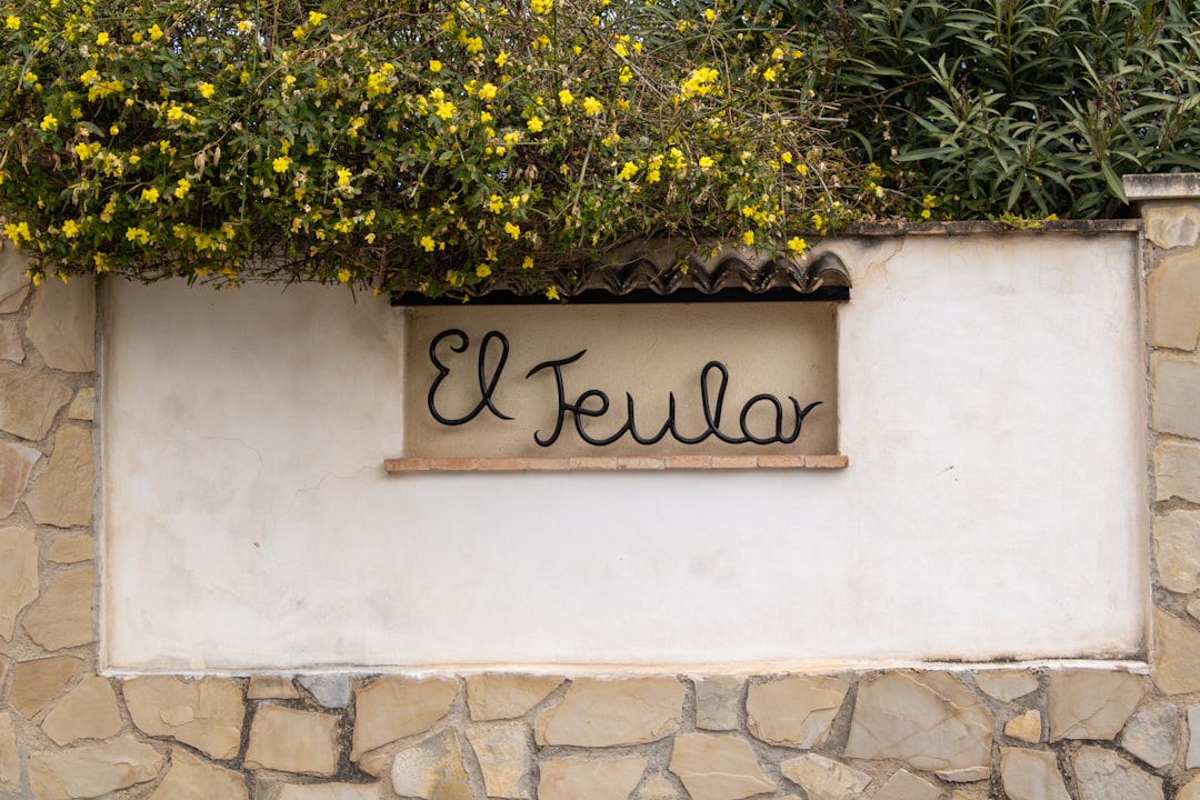 The sign "el teular" sits on a stone wall.