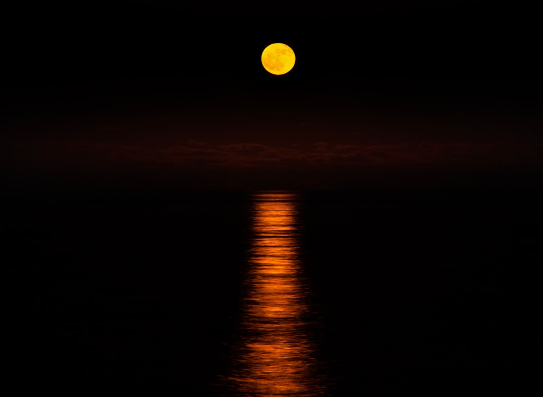 a full moon is reflected in the water